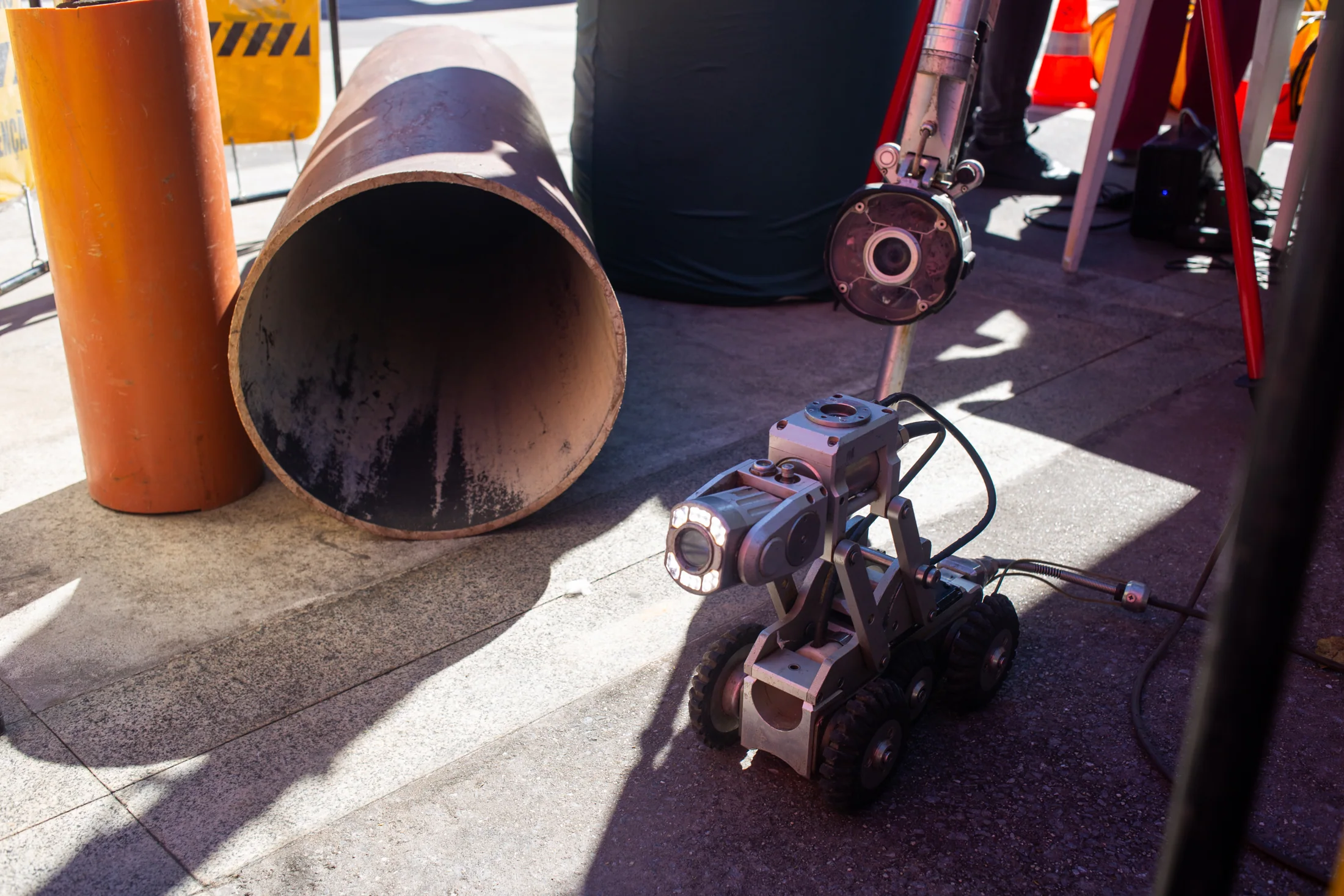 Wheeled sewer inspection camera beside pipe sections.