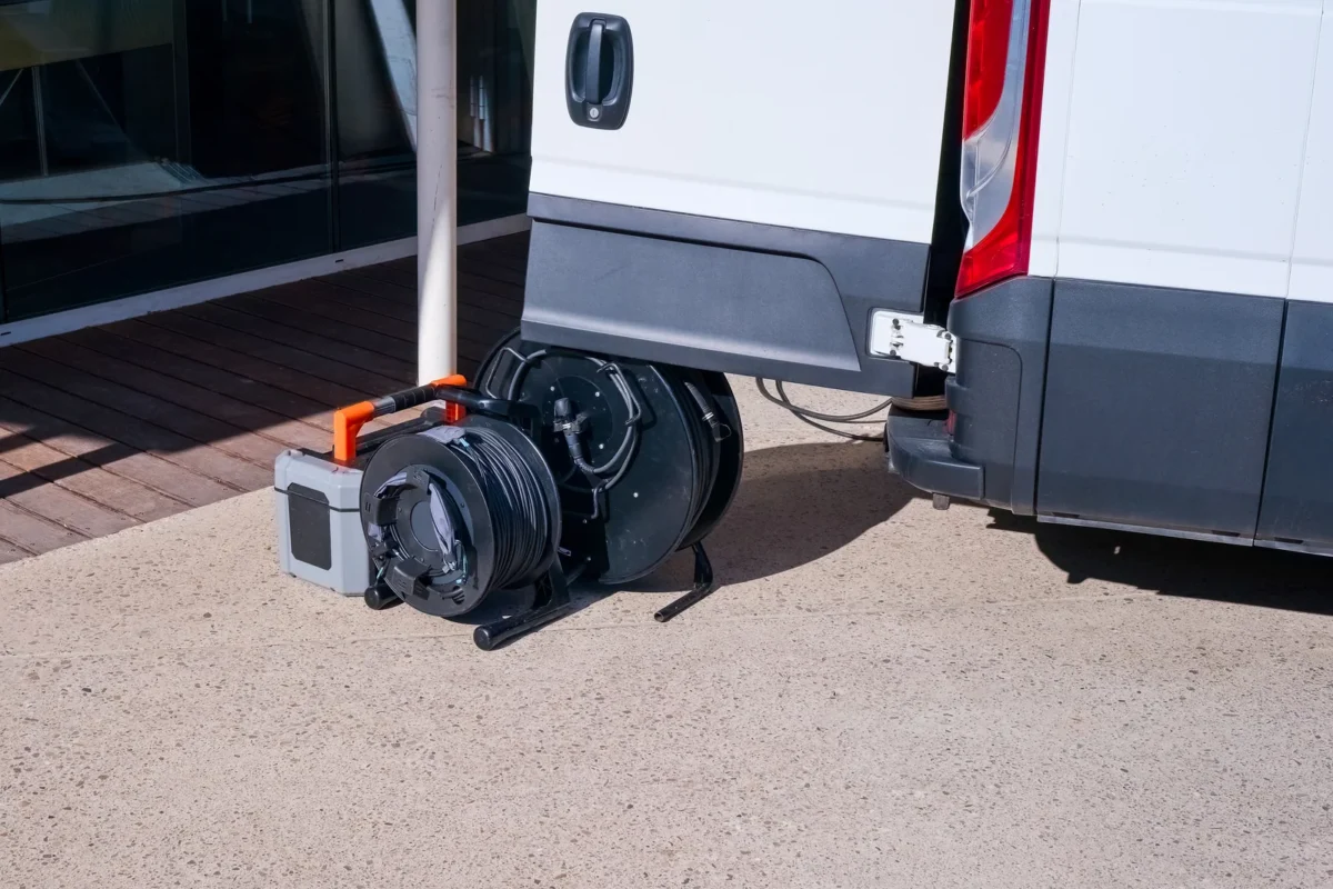 Drain survey camera and cable reel beside a service van.